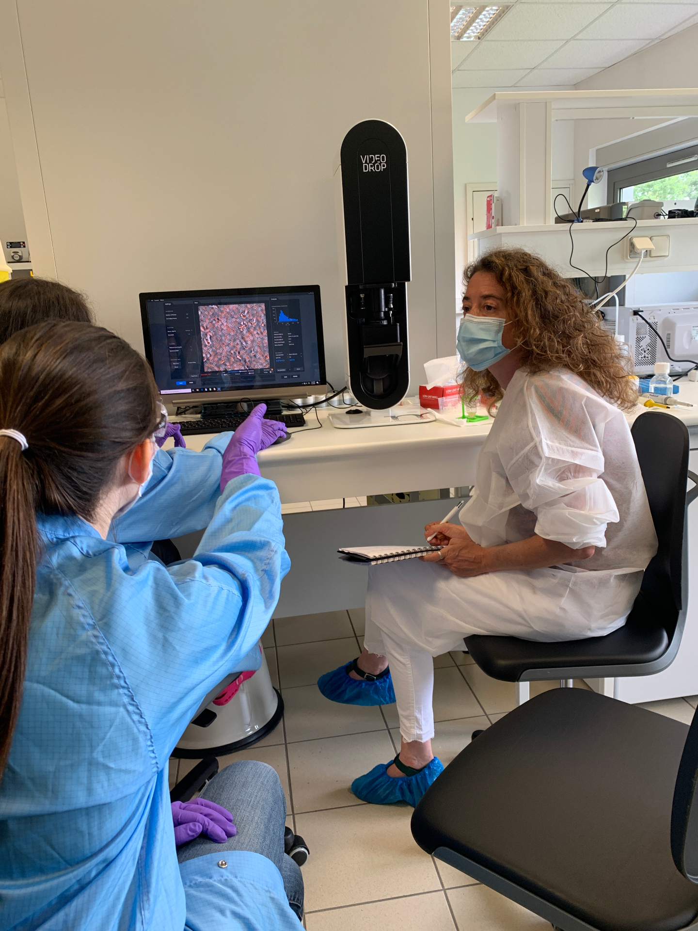 Deux scientifiques en tenue de laboratoire échangent devant l'écran du Videodrop affichant une analyse d'échantillon