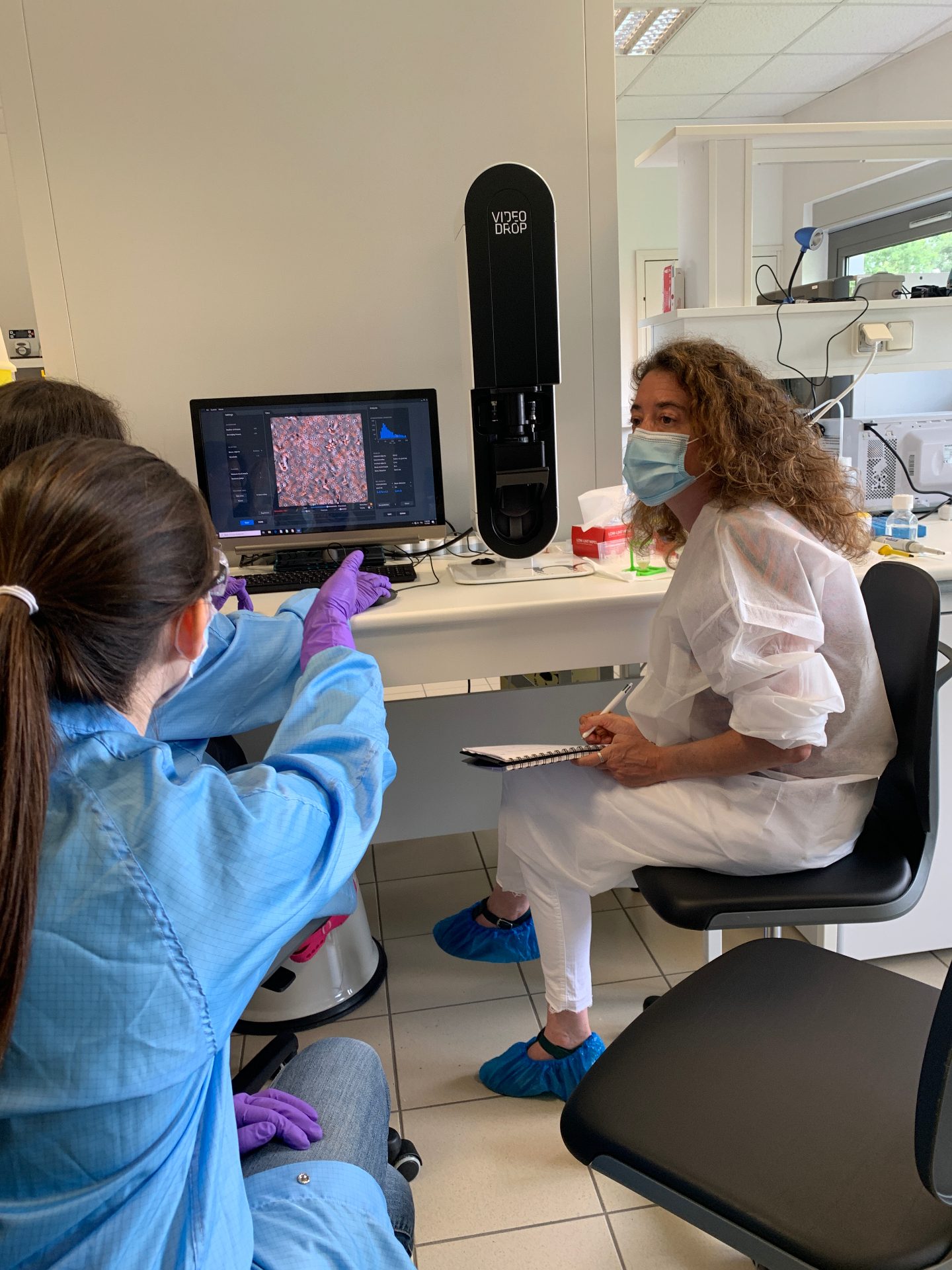 Deux scientifiques en tenue de laboratoire échangent devant l'écran du Videodrop affichant une analyse d'échantillon