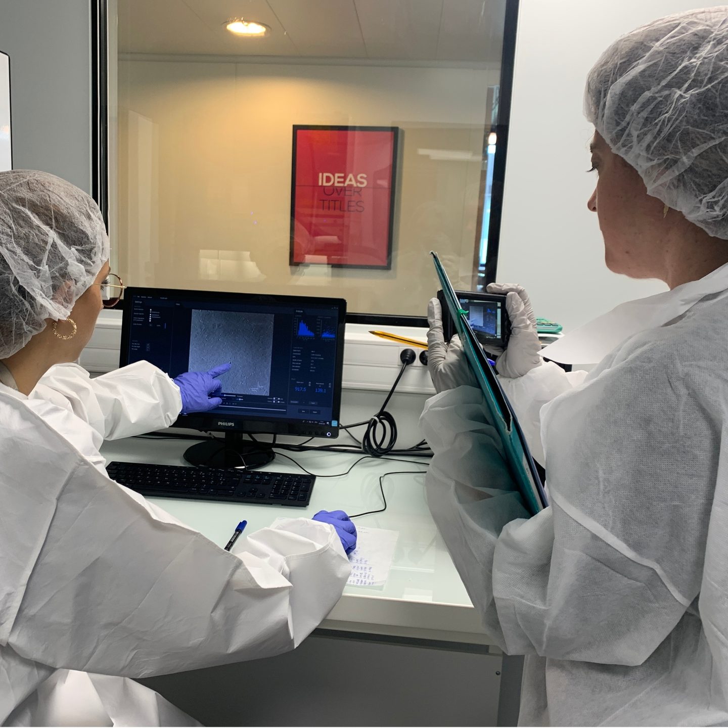Scientifiques en combinaison stérile observant les résultats du Videodrop et documentant l'analyse en laboratoire